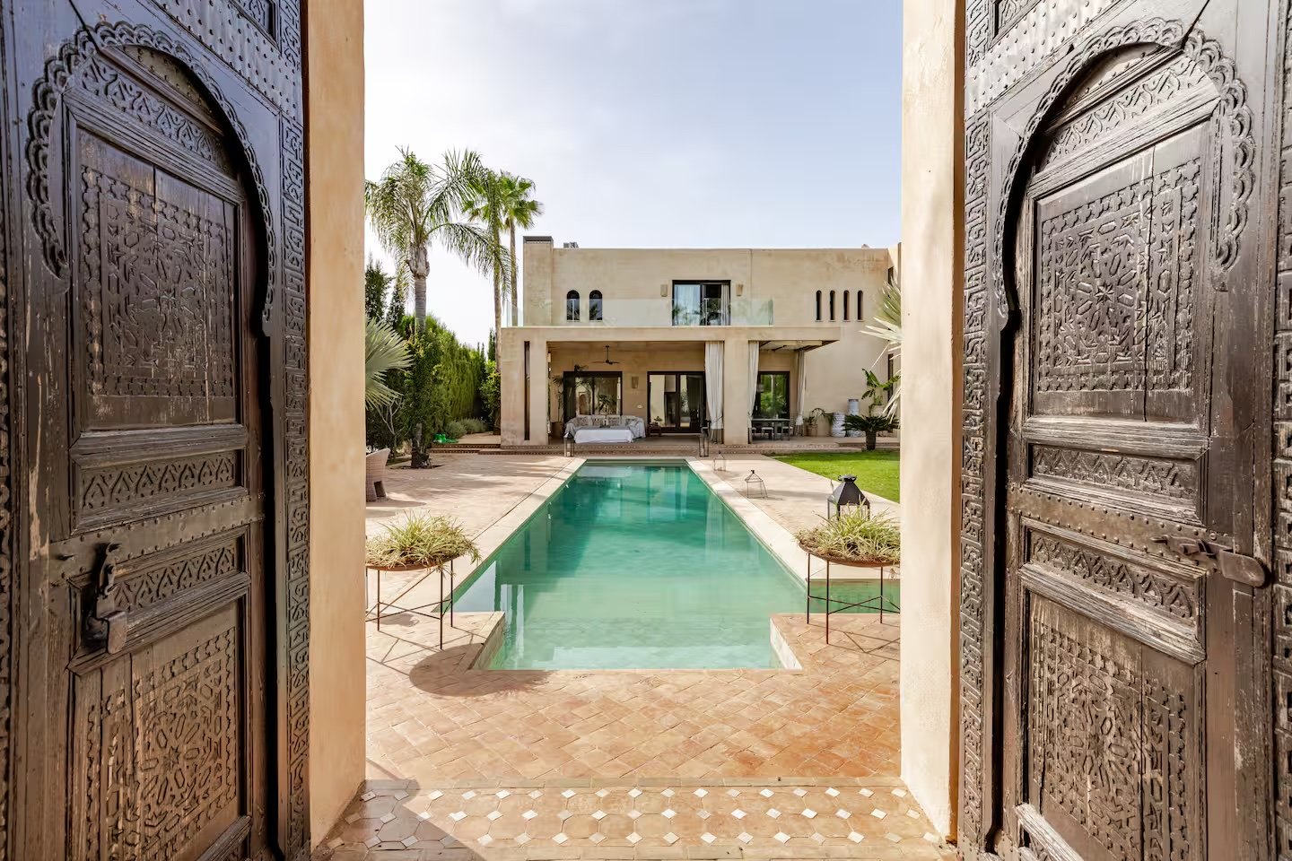 View through carved Andalusian doors onto a private villa and pool
